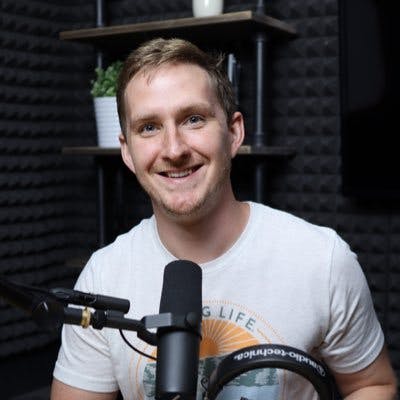 Alban Brooke sitting behind a podcast mic