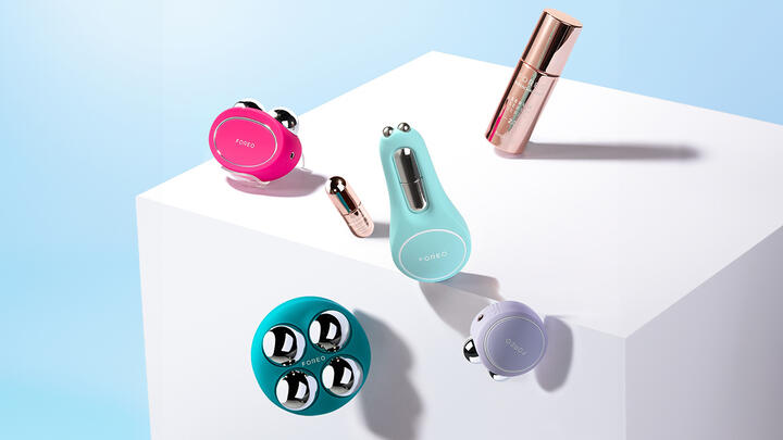 FOREO BEAR 2, BEAR 2 body, BEAR 2 go, BEAR eyes&lips, SUPERCHARGED Serum, SUPERCHARGED Eye & Lip Contour Booster floating over a white cube on a light blue background