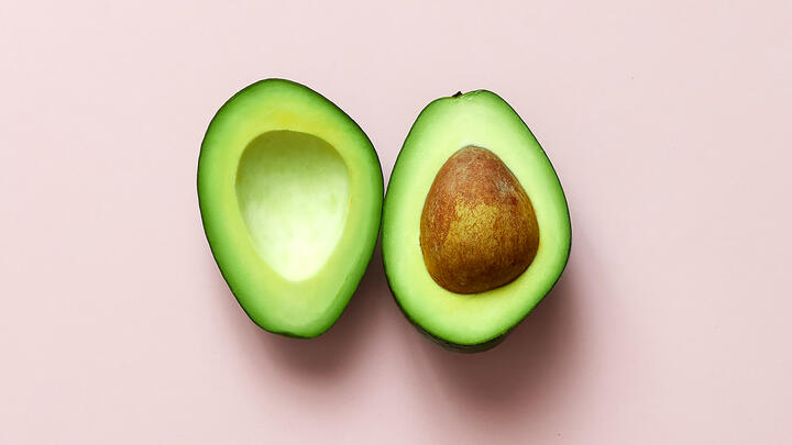 Halved avocado on a pink surface