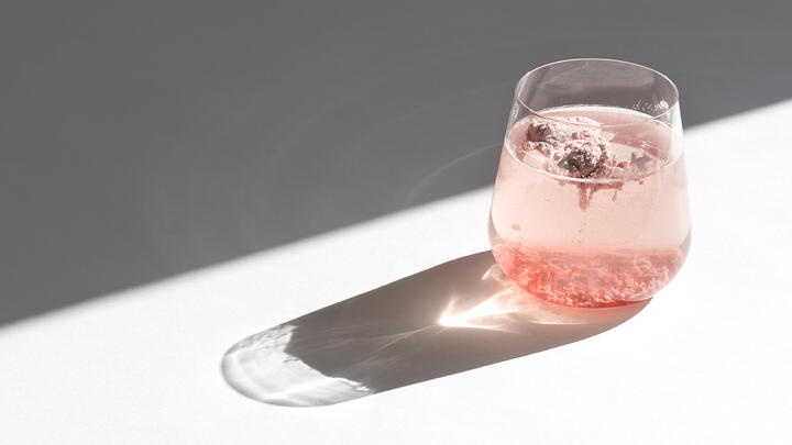 A glass filled with water and pink powder on a white surface