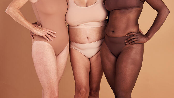 Closeup of lower parts of three women's bodies of various ages, constitutions, and skin colors.